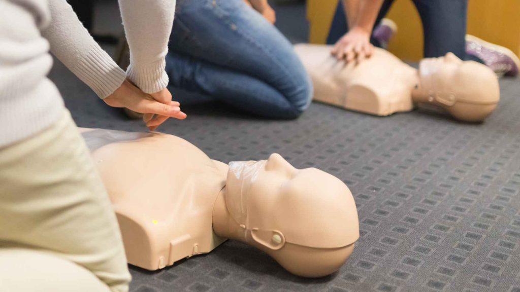 close up of students practicing cpr on manikins in a classroom