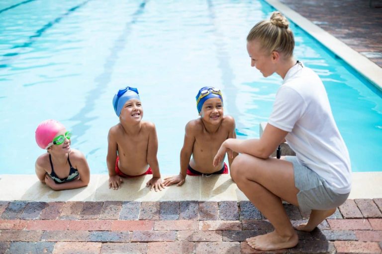 Swimming Lessons for Kids in Canada – Instructor teaching water safety to children during a swim class at the pool.