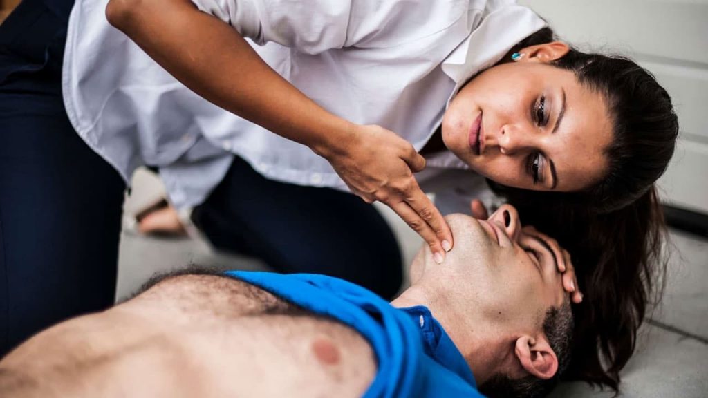 a woman checking for breathing on an unconscious person