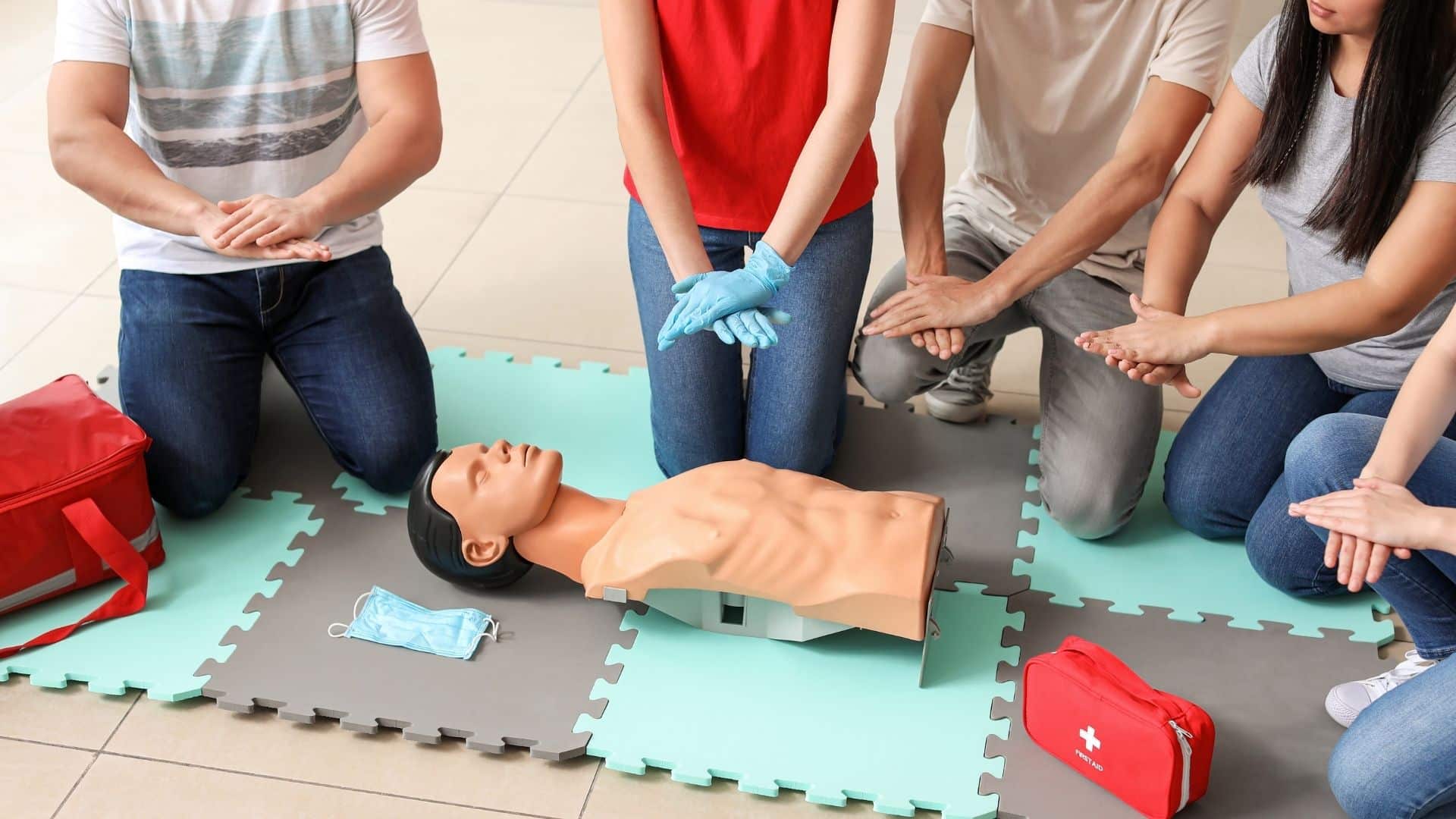 A group of people learning CPR techniques on a training mannequin during a first aid course.