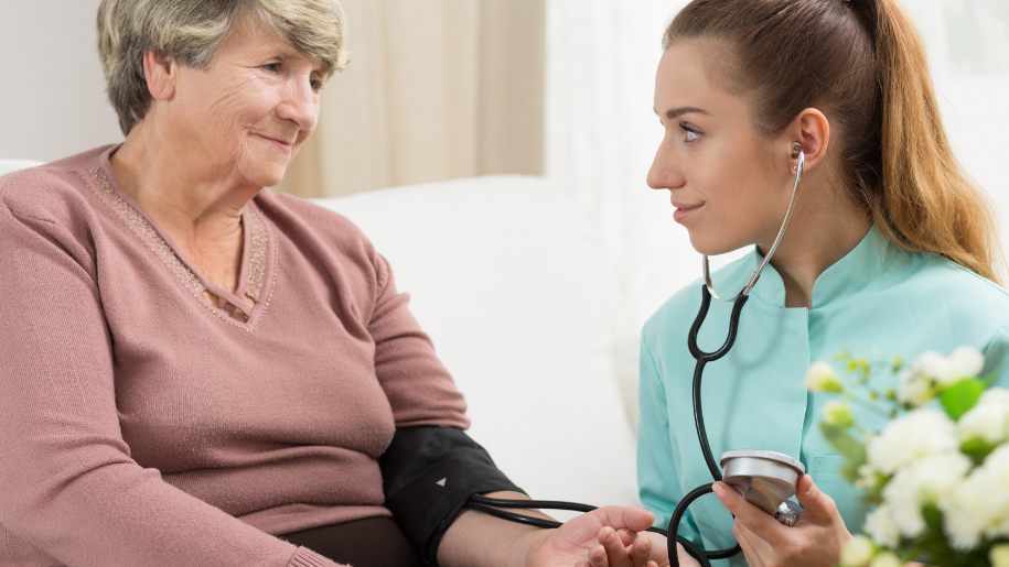 A PSW worker helping an elderly woman by checking her pulse and heartbeat.