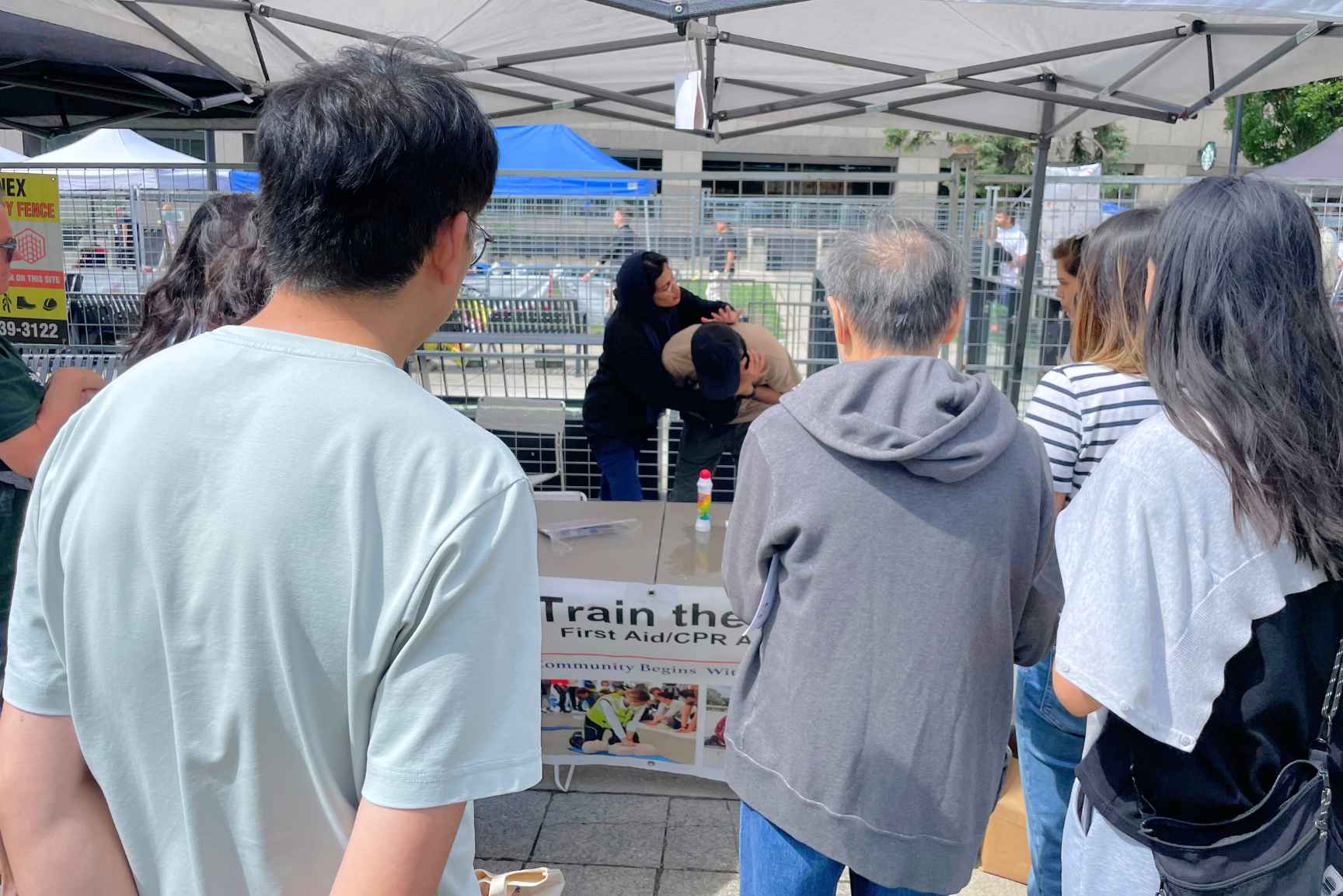 People learning about emergency choking response techniques, as a woman demonstrates on a man.