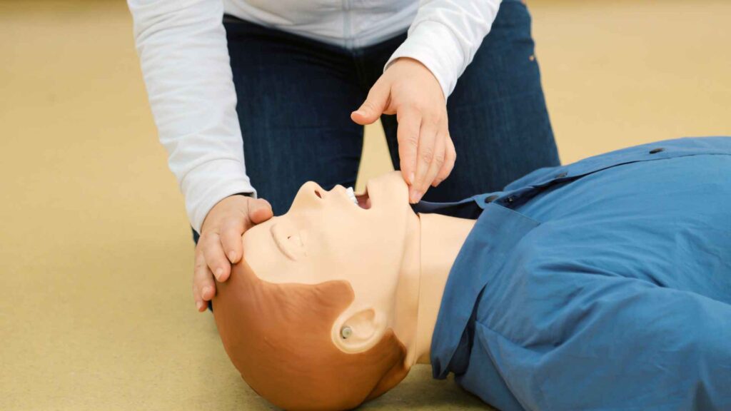 A person in a first aid course learning how to open an airway