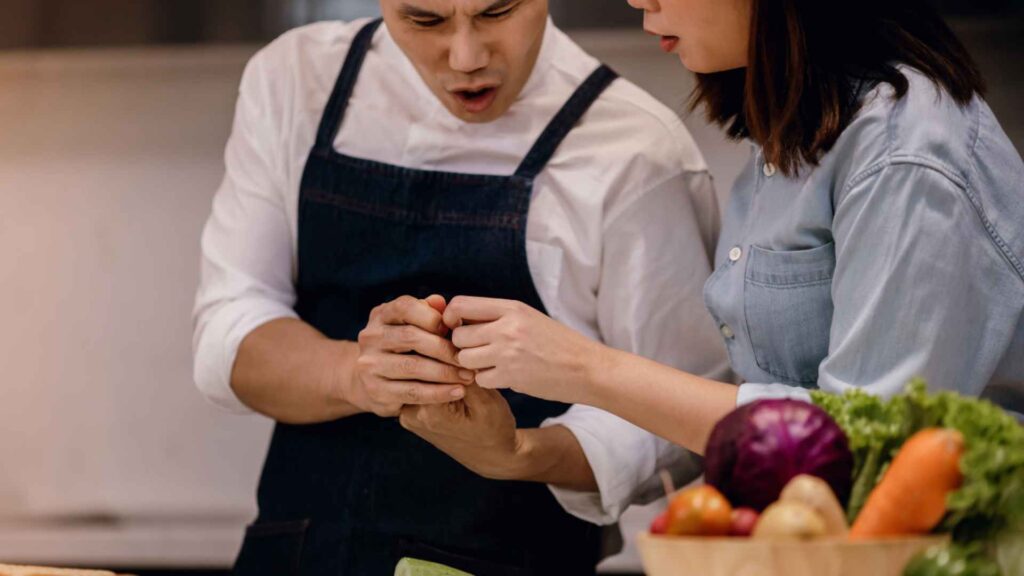 Two people in the kitchen, with one comforting the other after a cooking accident