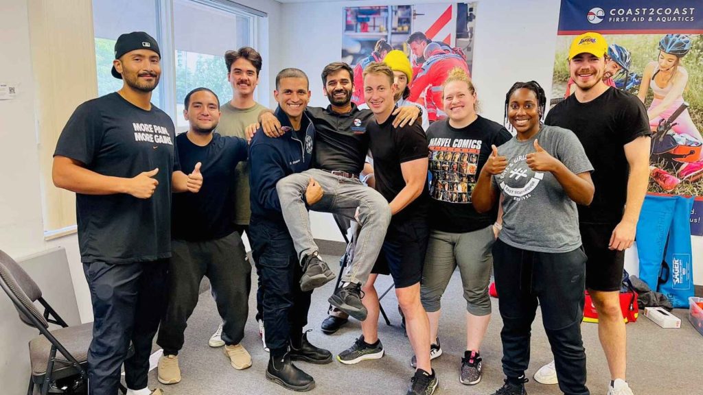 coast2coast first aid and cpr students happy in a group photo holding their instructor up in the middle
