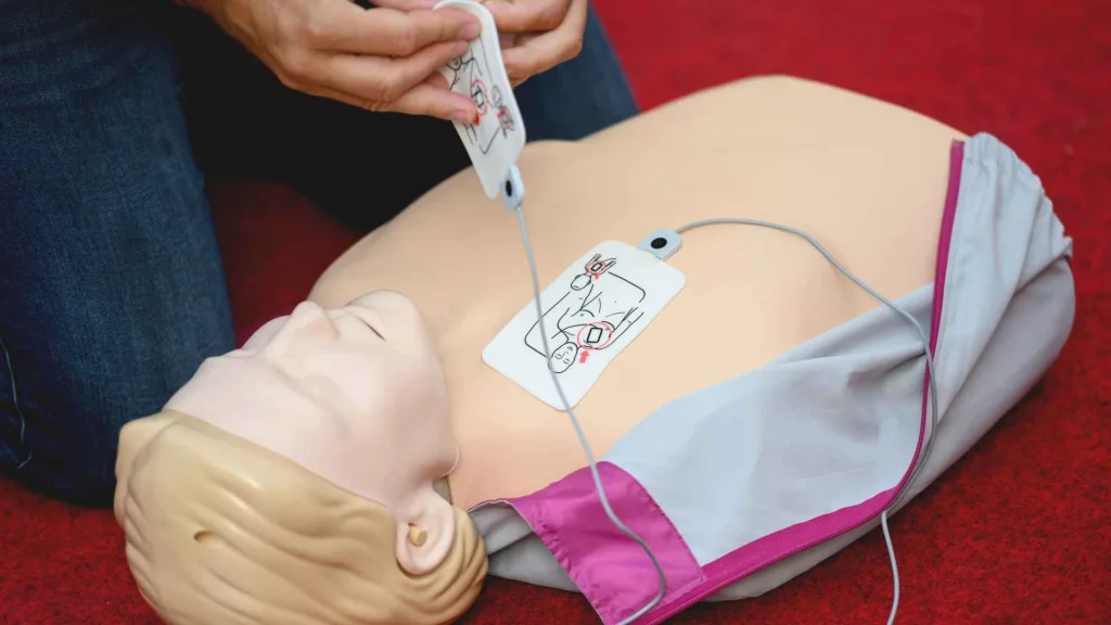 person placing aed pads on a cpr manikin