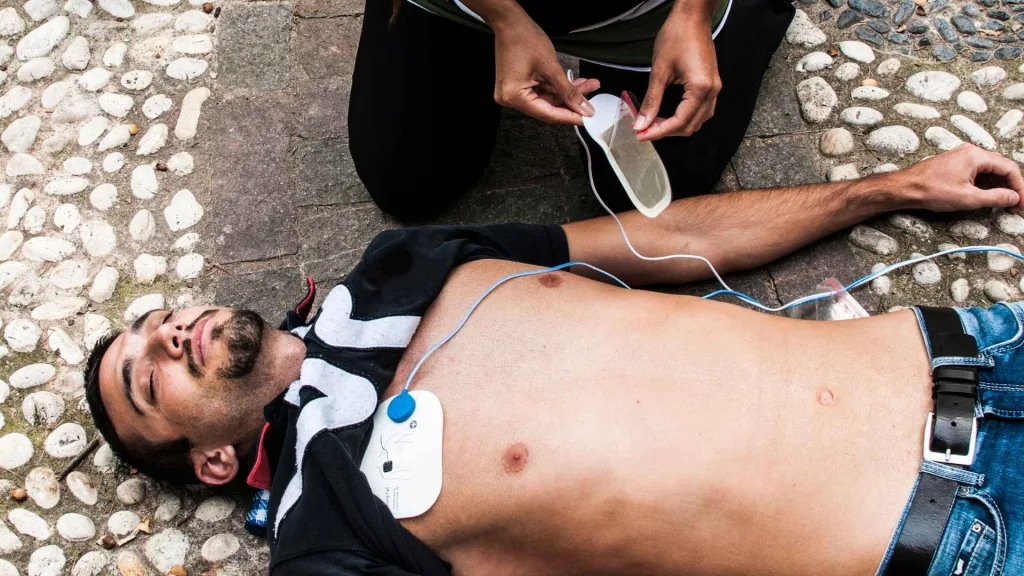 woman placing aed pads on an unconscious man