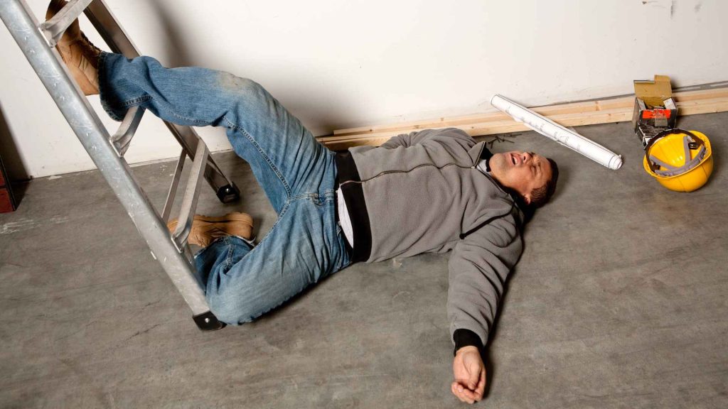 man who is laying on the floor after falling off of a ladder