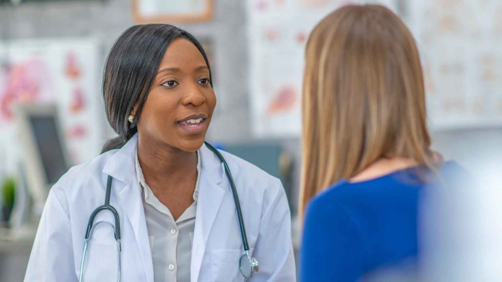 woman in blue shirt talking to a female doctor