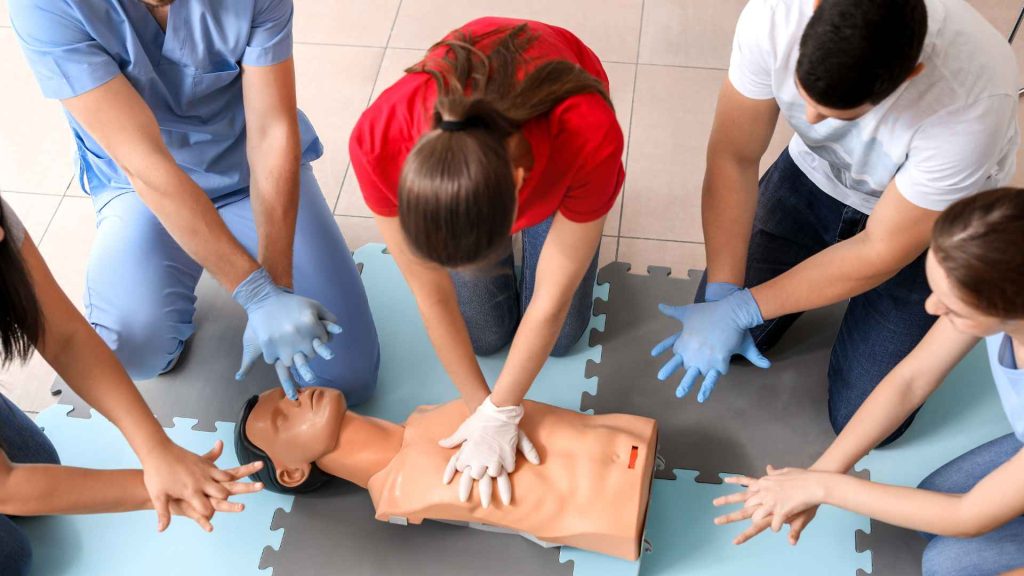 cpr instructor showing students how to perform cpr on a manikin