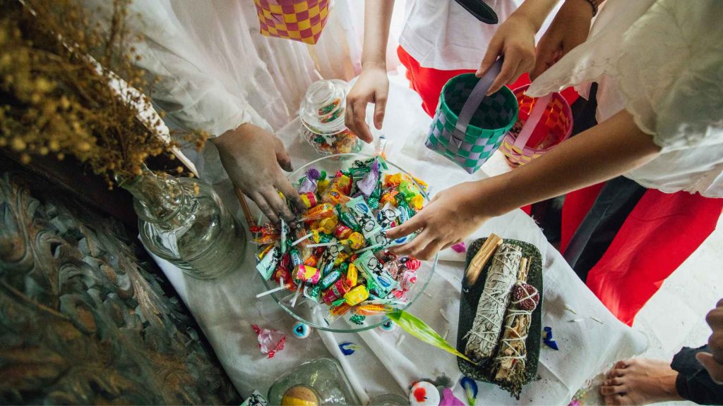 people's hands reaching into a bowl of halloween candy