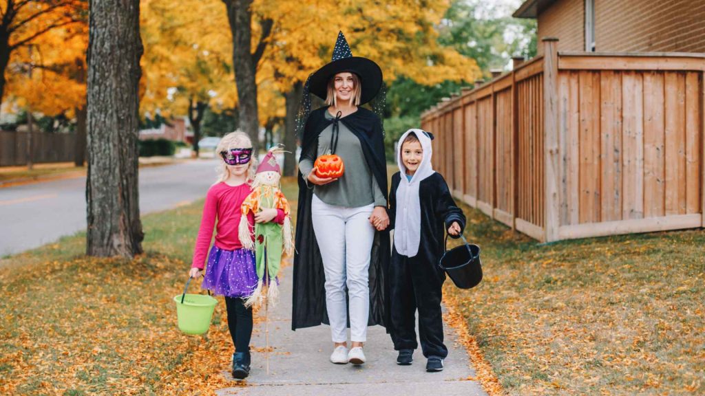 2 kids and a mom in costumes trick-or-treating for halloween