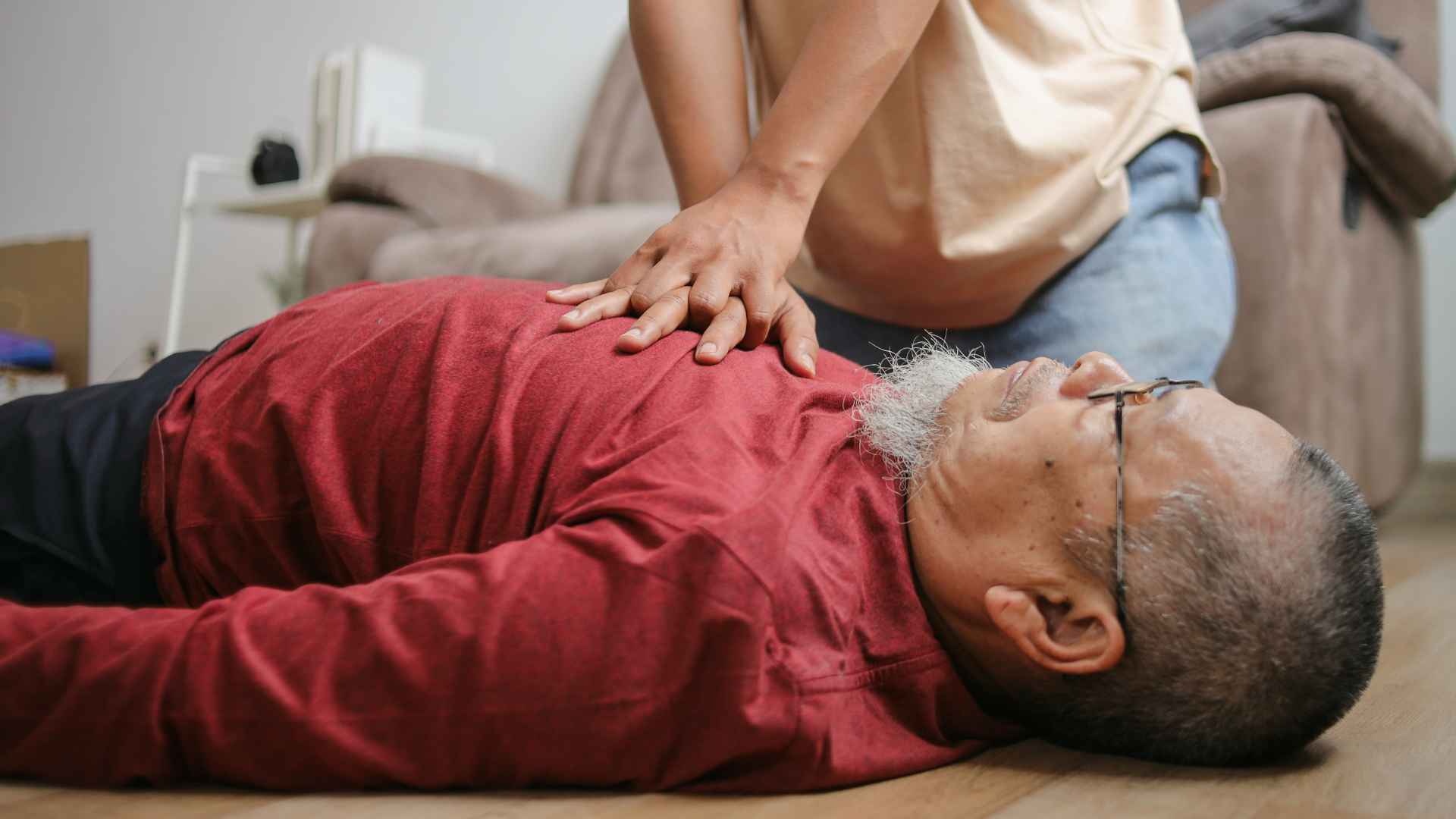 a man laying on the floor unconscious and a woman performing cpr on him