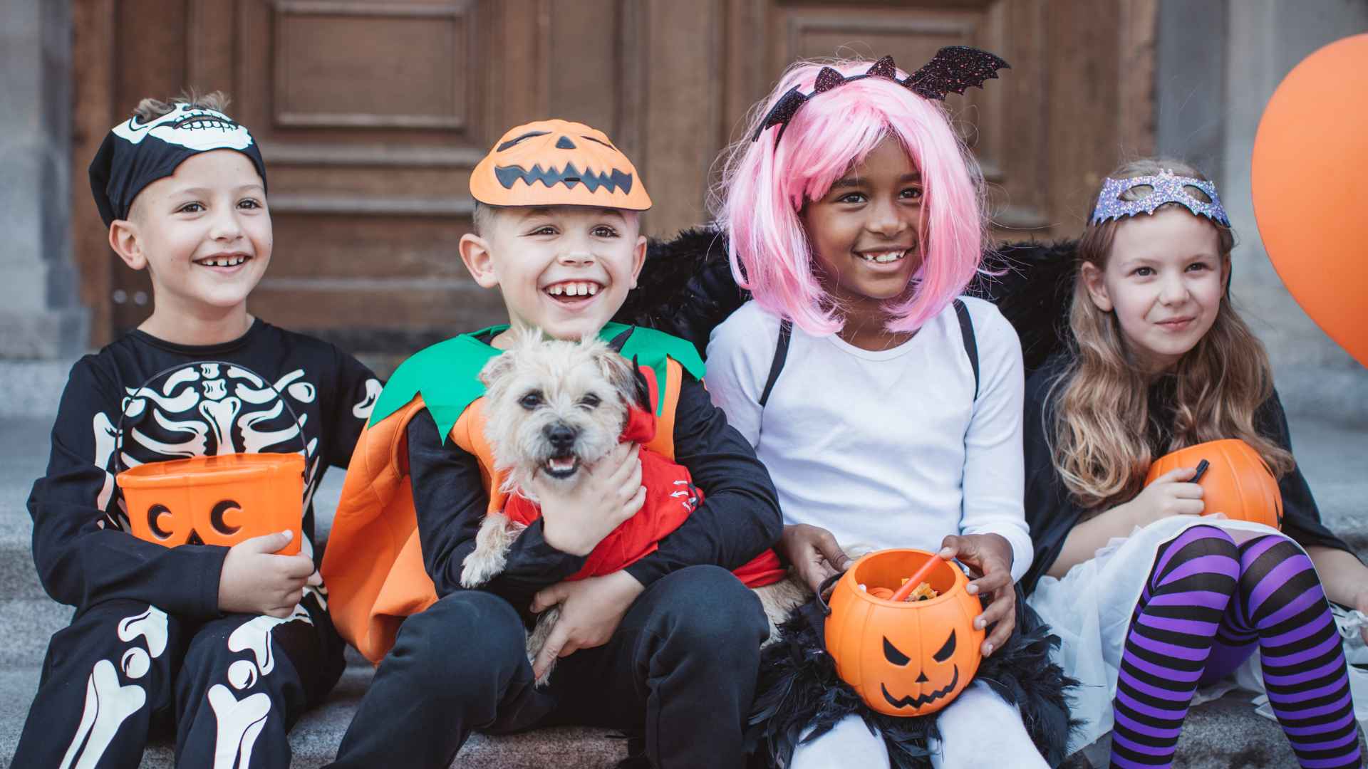 4 children sitting in halloween costumes smiling and laughing
