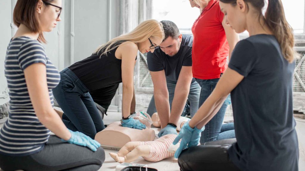 a small group of people practicing cpr on a manikin