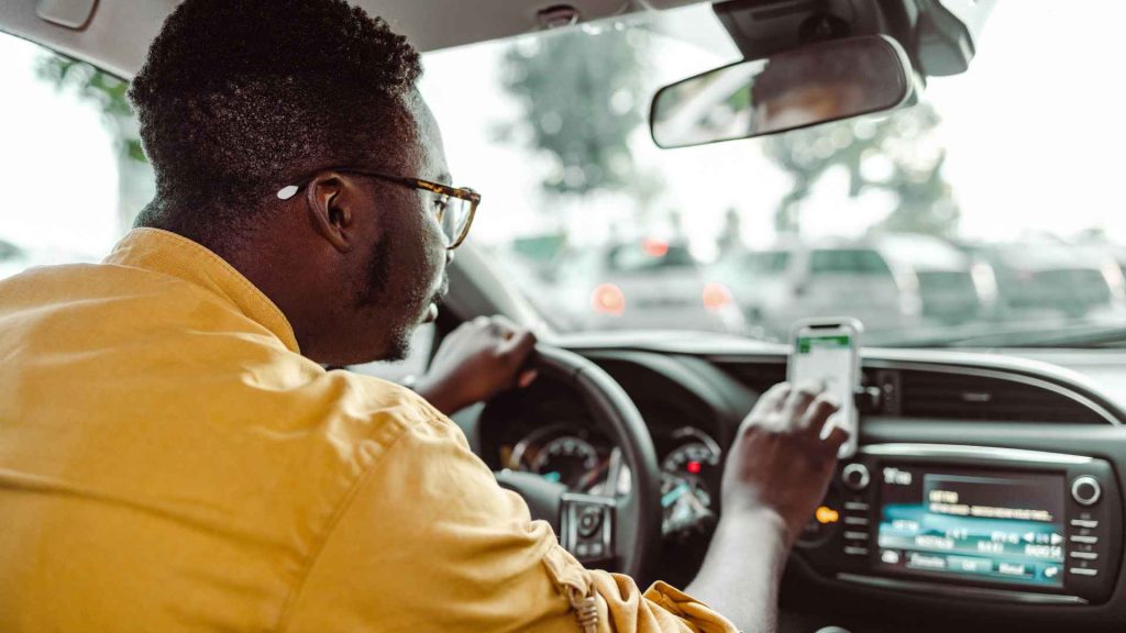 man driving in a vehicle looking at his phone distracted