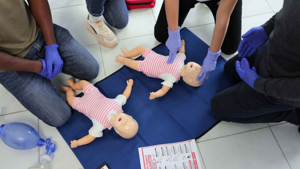 people performing cpr on infant manikins in a first aid and cpr training course