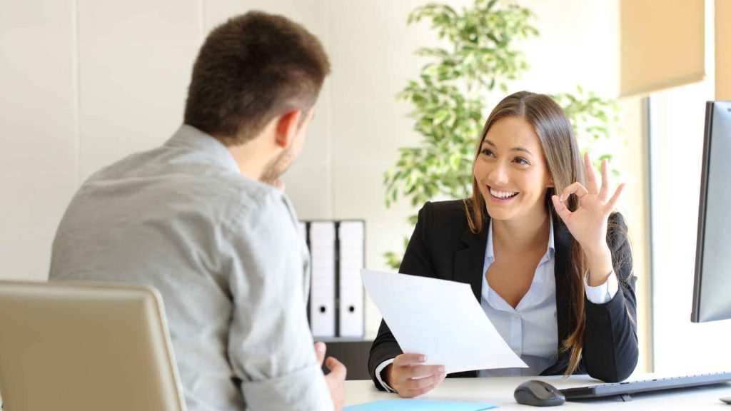 young woman interviewing a man. she is holding his resume